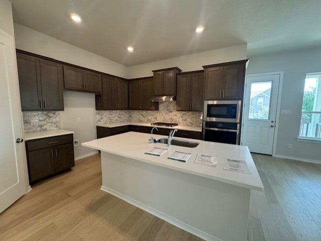 2705 Sage Ranch Dr Unit 6, Leander, TX 78641 - kitchen featuring stainless steel appliances, under cabinet range hood, light wood finished floors, dark brown cabinets, and recessed lighting