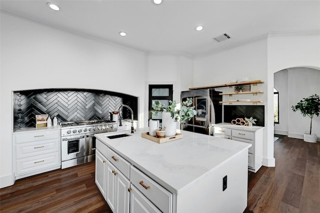 kitchen with visible vents, an island with sink, double oven range, white cabinetry, and a sink