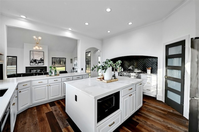 kitchen featuring arched walkways, pendant lighting, dark wood-type flooring, white cabinets, and a kitchen island