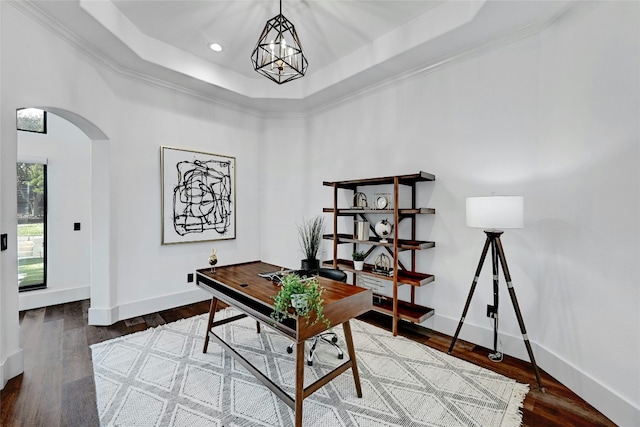 office space featuring dark wood-style floors, arched walkways, baseboards, and a tray ceiling