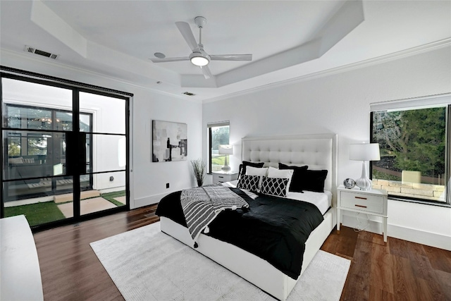 bedroom featuring dark wood-type flooring, a raised ceiling, visible vents, and baseboards