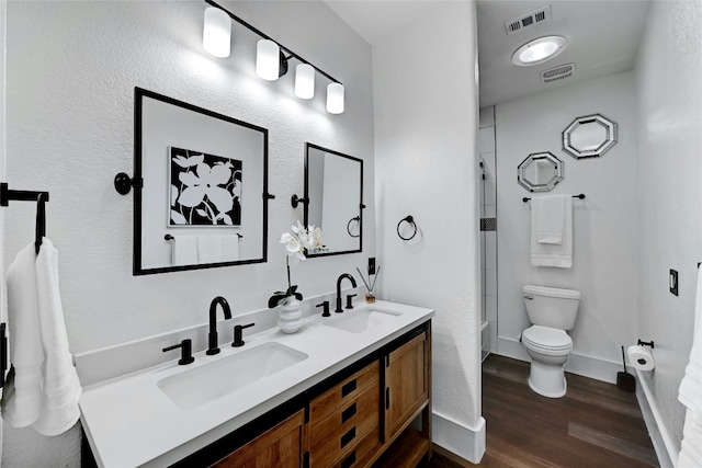 bathroom featuring toilet, wood finished floors, a sink, and visible vents