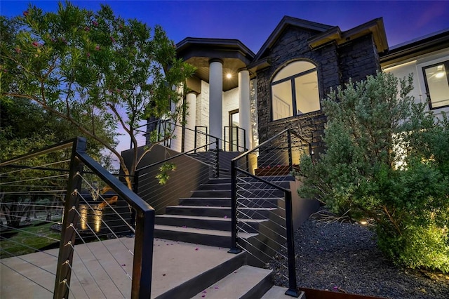 view of front of home featuring stone siding, stairway, and stucco siding