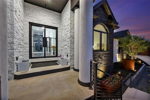 property entrance with stone siding, french doors, and stucco siding