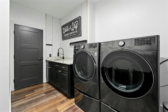 washroom with dark wood finished floors, a sink, cabinet space, and washer and dryer