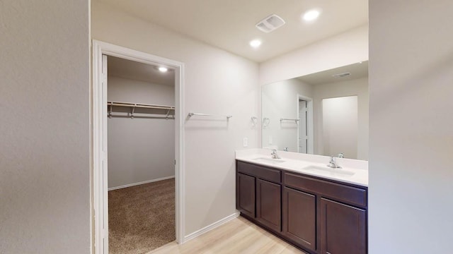 bathroom featuring visible vents, a sink, baseboards, and double vanity