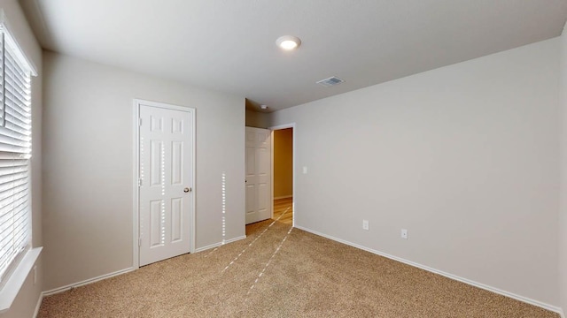 unfurnished bedroom with light colored carpet, a closet, visible vents, and baseboards