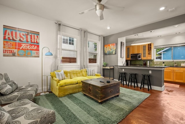 living area featuring finished concrete flooring, ceiling fan, and recessed lighting