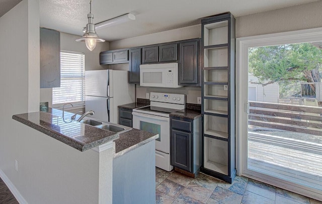 kitchen with hanging light fixtures, a sink, a textured ceiling, white appliances, and a peninsula