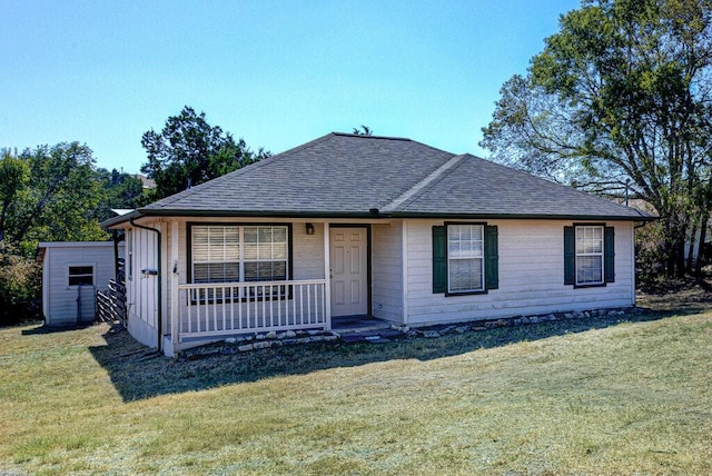 view of front facade featuring covered porch, a shingled roof, a front lawn, and an outdoor structure