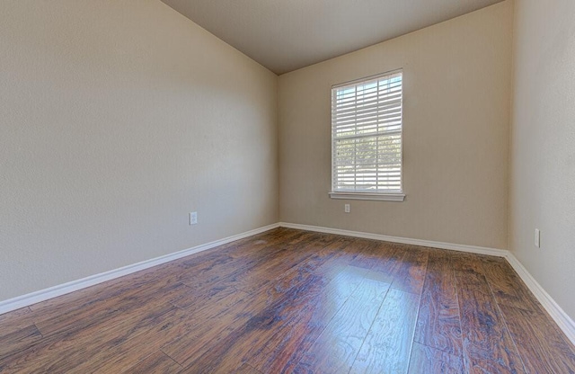 unfurnished room featuring lofted ceiling, dark wood-style flooring, and baseboards