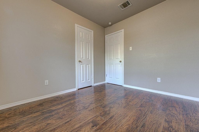 spare room featuring baseboards, visible vents, and dark wood-style flooring