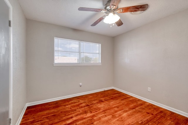 unfurnished room with a textured ceiling, wood finished floors, a ceiling fan, and baseboards