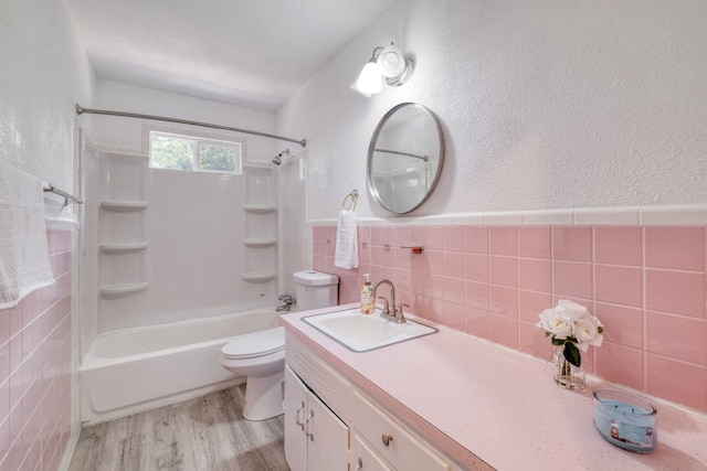 full bath featuring tile walls, toilet, vanity, shower / tub combination, and wood finished floors