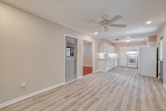 kitchen with light countertops, freestanding refrigerator, white cabinets, light wood-type flooring, and range