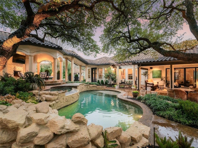 pool at dusk with an in ground hot tub, a patio area, and an outdoor pool