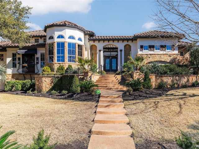 mediterranean / spanish home featuring a tile roof, stone siding, and stucco siding