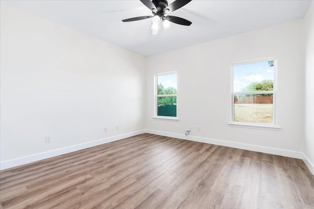 empty room with ceiling fan, light wood finished floors, and baseboards