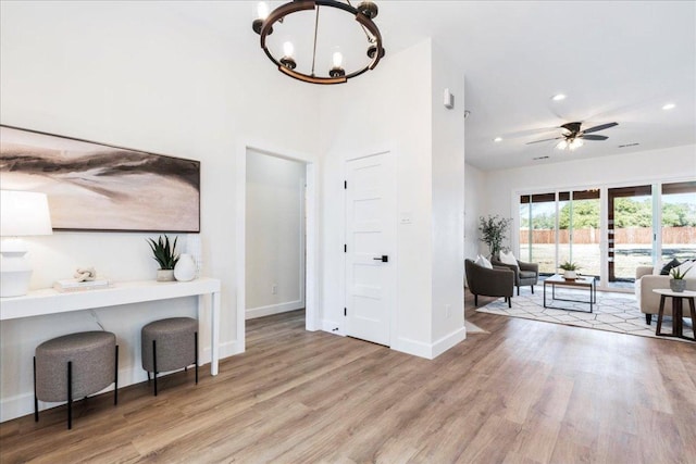 foyer with ceiling fan with notable chandelier, recessed lighting, baseboards, and wood finished floors