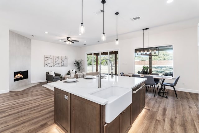 kitchen with wood finished floors, a tile fireplace, a sink, and visible vents