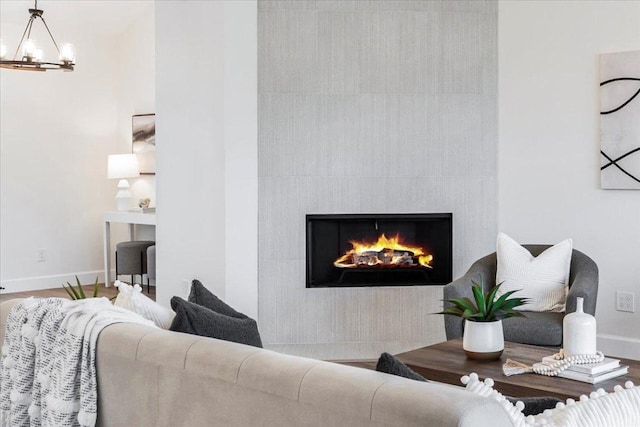 living area featuring a fireplace, baseboards, and an inviting chandelier