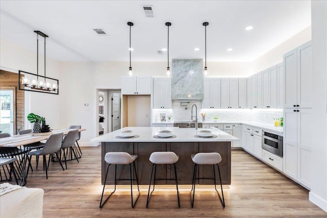 15400 Fm 1826, Austin, TX 78737 - kitchen with light wood-type flooring, ventilation hood, tasteful backsplash, light countertops, and white cabinets