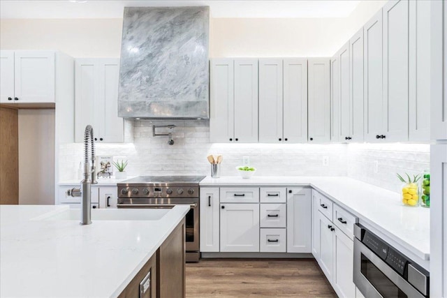 15400 Fm 1826, Austin, TX 78737 - kitchen featuring appliances with stainless steel finishes, white cabinets, decorative backsplash, light stone counters, and wood finished floors