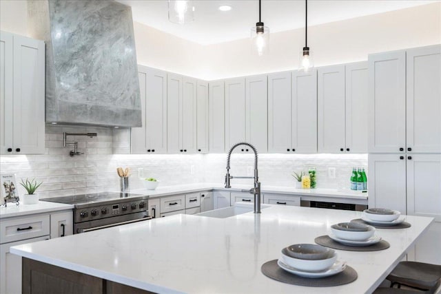 kitchen with a kitchen bar, an island with sink, stainless steel range, a sink, and tasteful backsplash