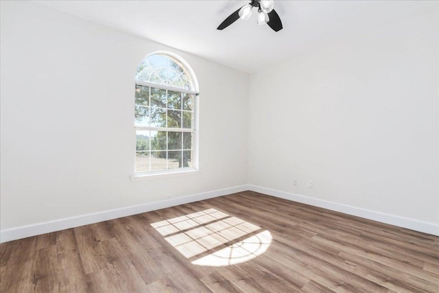 empty room with a ceiling fan, baseboards, and wood finished floors