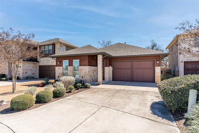 view of front of home featuring a garage, concrete driveway, stone siding, roof with shingles, and fence