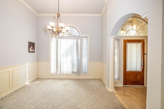 entryway featuring a chandelier, light colored carpet, ornamental molding, and ornate columns