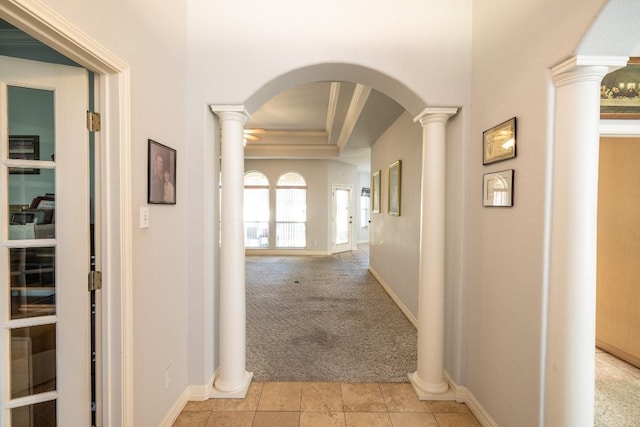 hallway featuring arched walkways, light tile patterned floors, light carpet, ornate columns, and crown molding