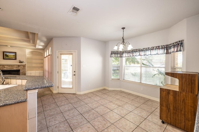 dining area with light tile patterned floors, baseboards, built in features, visible vents, and a brick fireplace