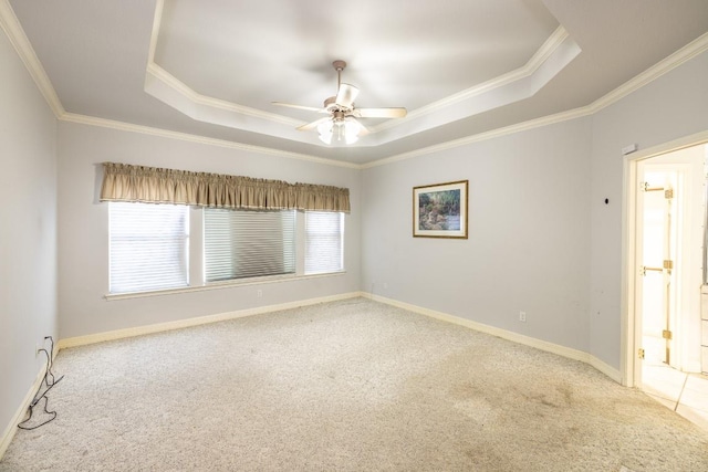 carpeted spare room featuring ornamental molding, a tray ceiling, and a wealth of natural light