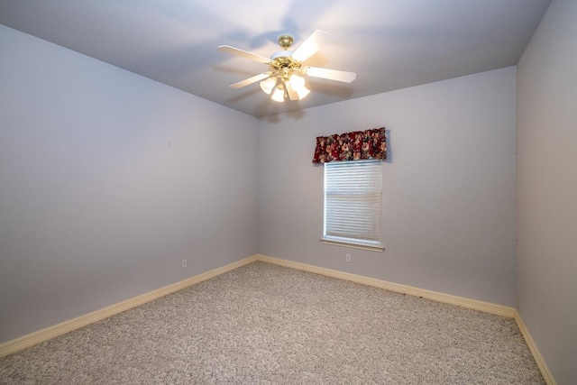 carpeted spare room with a ceiling fan and baseboards