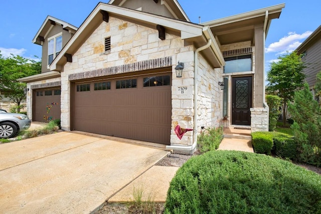 view of front of home with driveway and stone siding