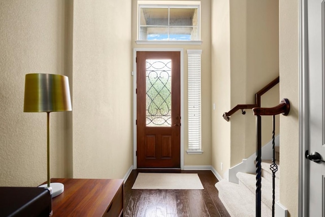 foyer featuring stairway, plenty of natural light, dark wood finished floors, and baseboards