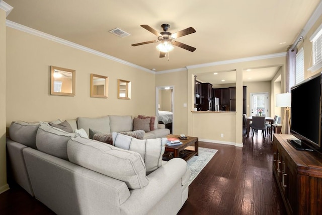 living area featuring crown molding, dark wood finished floors, visible vents, a ceiling fan, and baseboards