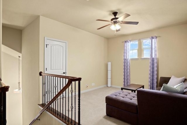 living area featuring baseboards, ceiling fan, an upstairs landing, and light colored carpet