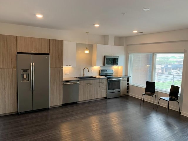 kitchen featuring stainless steel appliances, decorative light fixtures, a sink, and modern cabinets