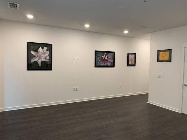 empty room featuring dark wood-type flooring, recessed lighting, visible vents, and baseboards