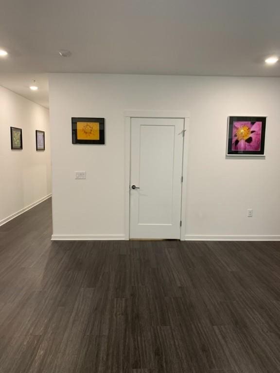 empty room with dark wood-type flooring, recessed lighting, and baseboards