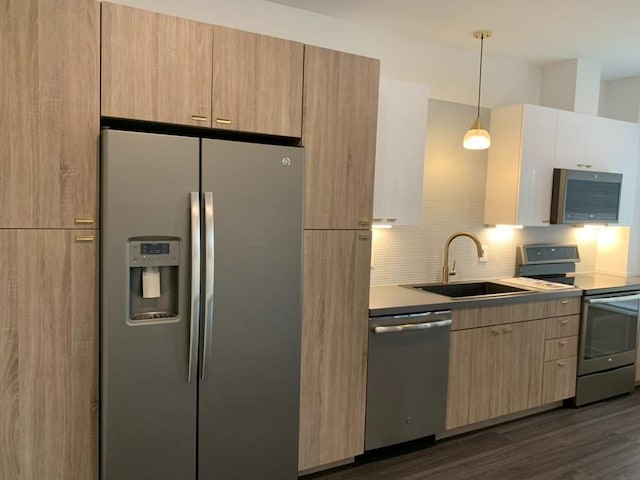 kitchen with appliances with stainless steel finishes, pendant lighting, light countertops, and modern cabinets