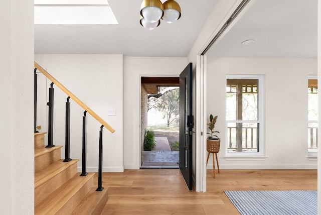 foyer with light wood finished floors, stairway, an inviting chandelier, and baseboards