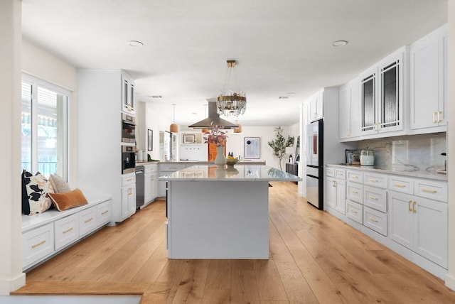 kitchen featuring a kitchen island, white cabinets, light countertops, appliances with stainless steel finishes, and pendant lighting