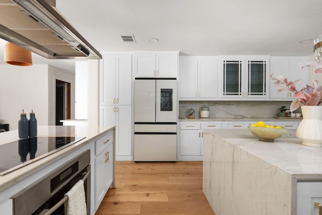 kitchen featuring glass insert cabinets, fridge, island exhaust hood, and white cabinetry