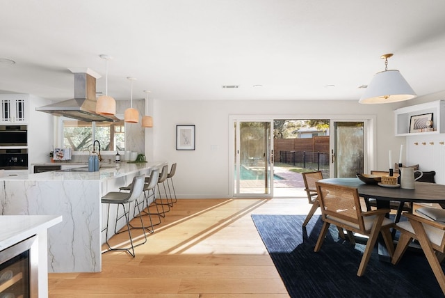 dining space featuring visible vents, wine cooler, light wood-style flooring, and baseboards