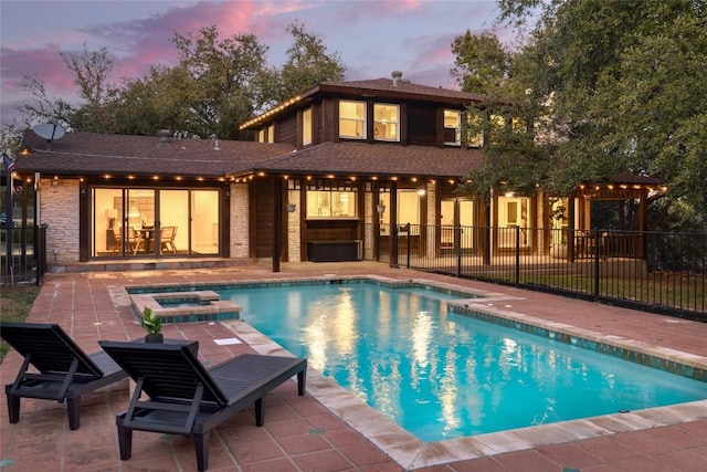 view of pool featuring a pool with connected hot tub, a patio area, and fence