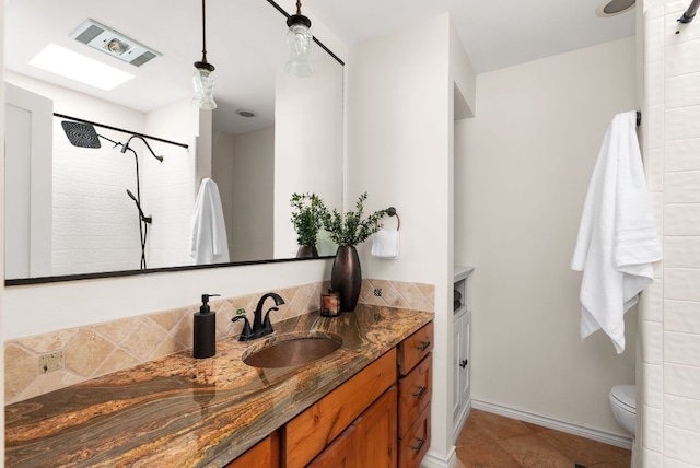 bathroom with visible vents, toilet, a tile shower, vanity, and baseboards