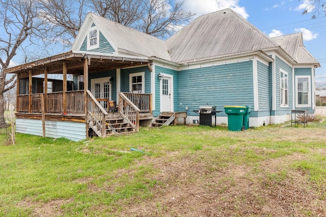 rear view of house featuring a porch, metal roof, and a lawn